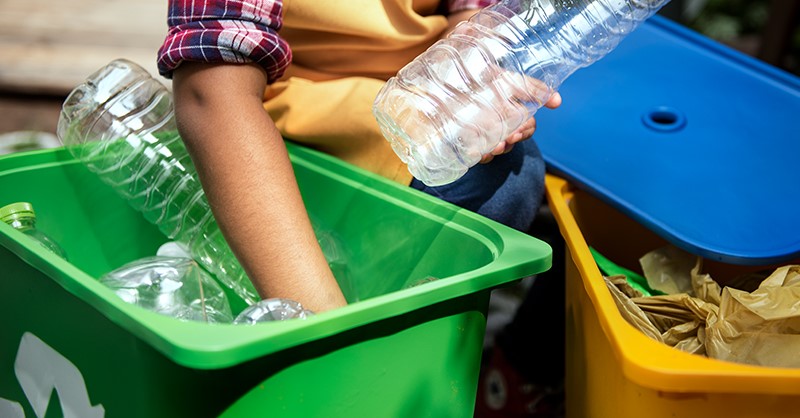 hand in green recycling bin